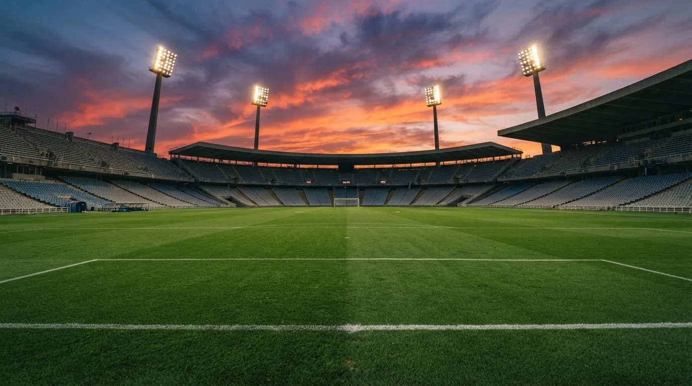 Un estadio de fútbol vacío con torres de iluminación al atardecer