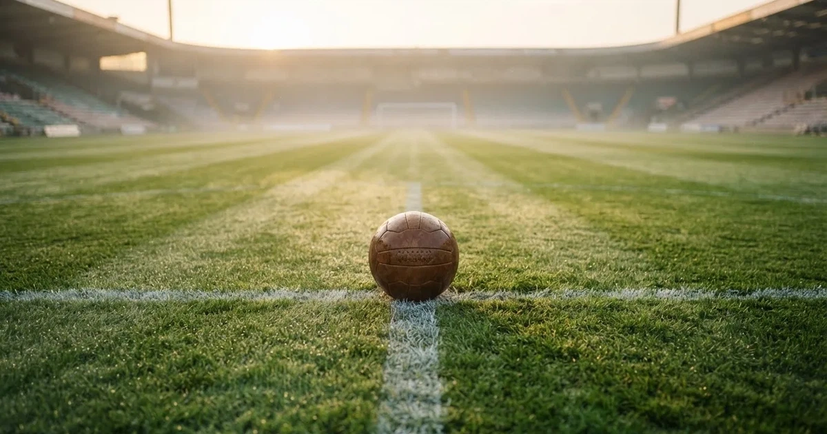 Un balón en el punto central de un campo de césped a la luz de la mañana