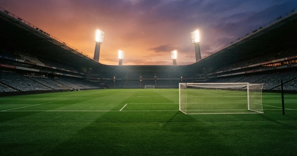 Un estadio de fútbol vacío con torres de iluminación al atardecer