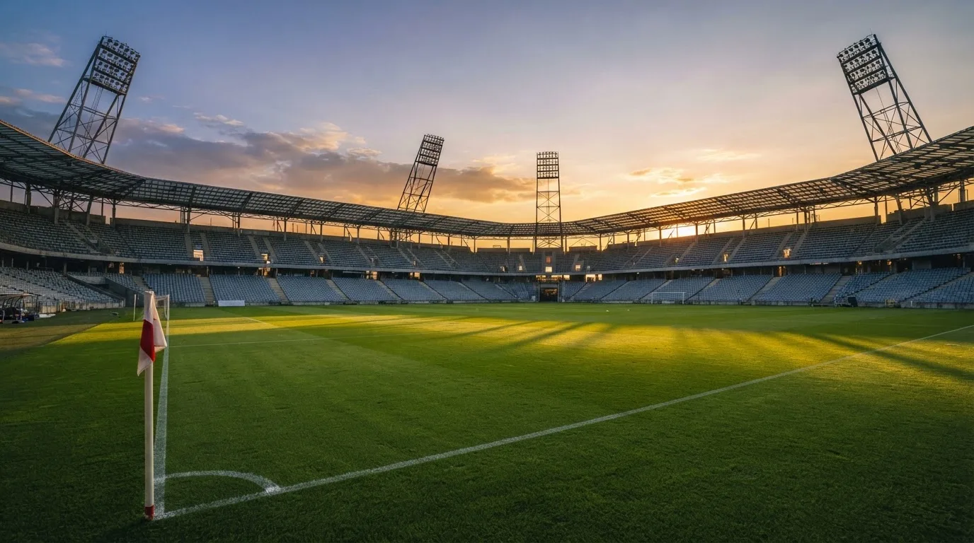 Un estadio de fútbol vacío con torres de iluminación al atardecer