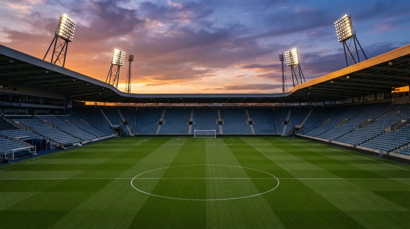 Un estadio de fútbol vacío con torres de iluminación al atardecer