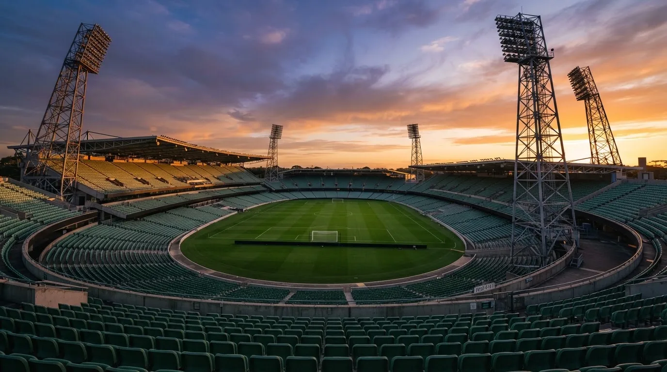 Un estadio de fútbol vacío con torres de iluminación al atardecer