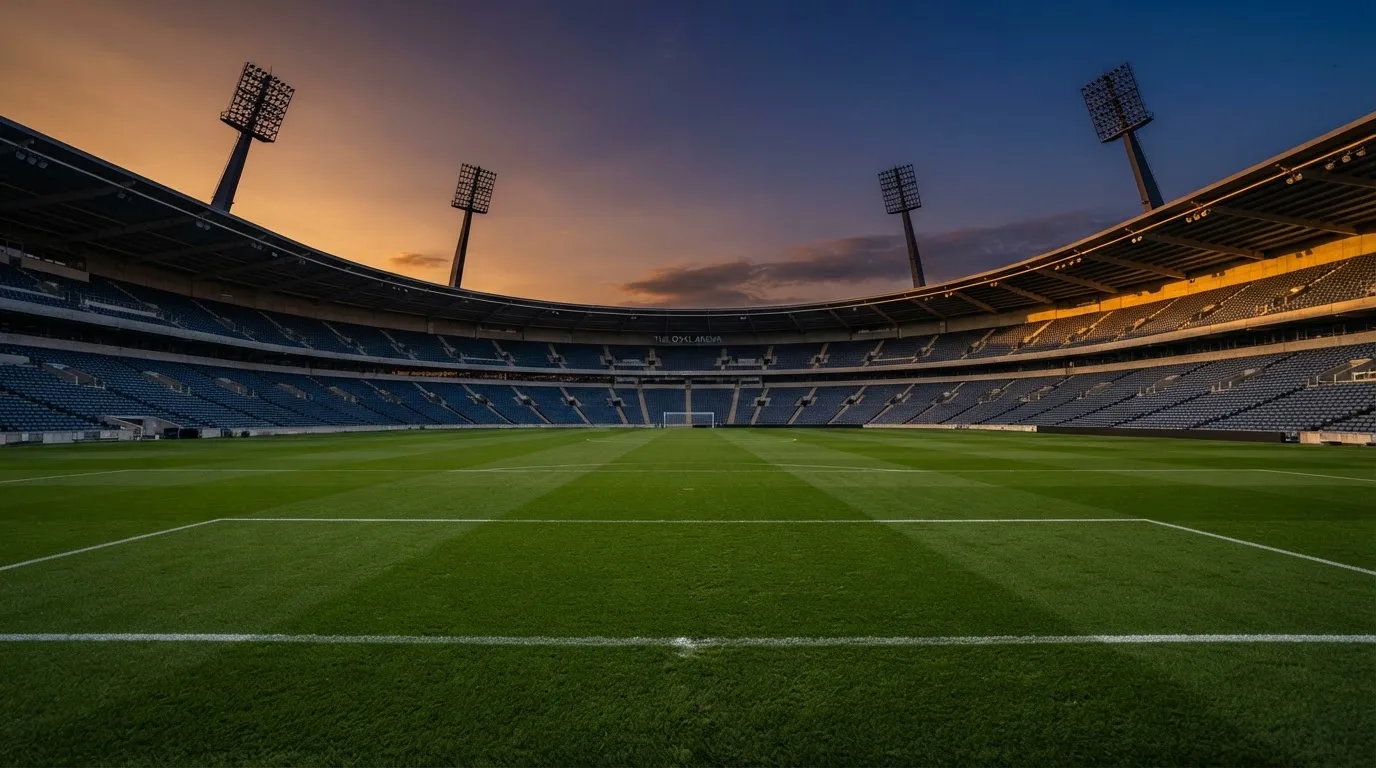 Un estadio de fútbol vacío con torres de iluminación al atardecer