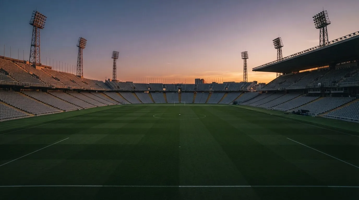 Un estadio de fútbol vacío con torres de iluminación al atardecer