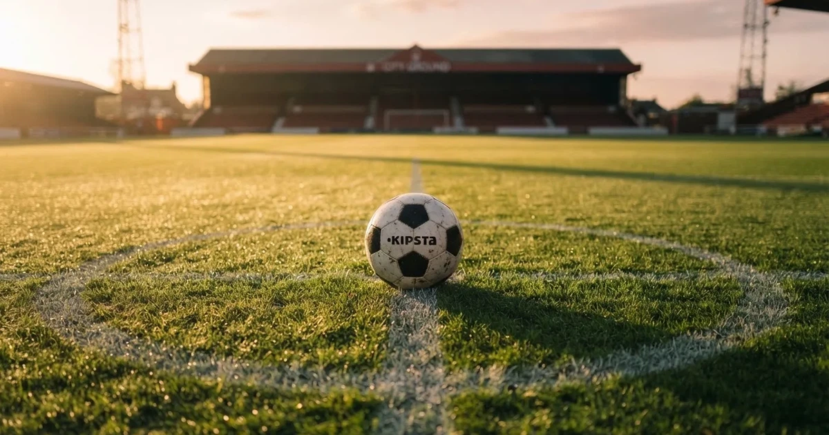 Un balón en el punto central de un campo de césped a la luz de la mañana