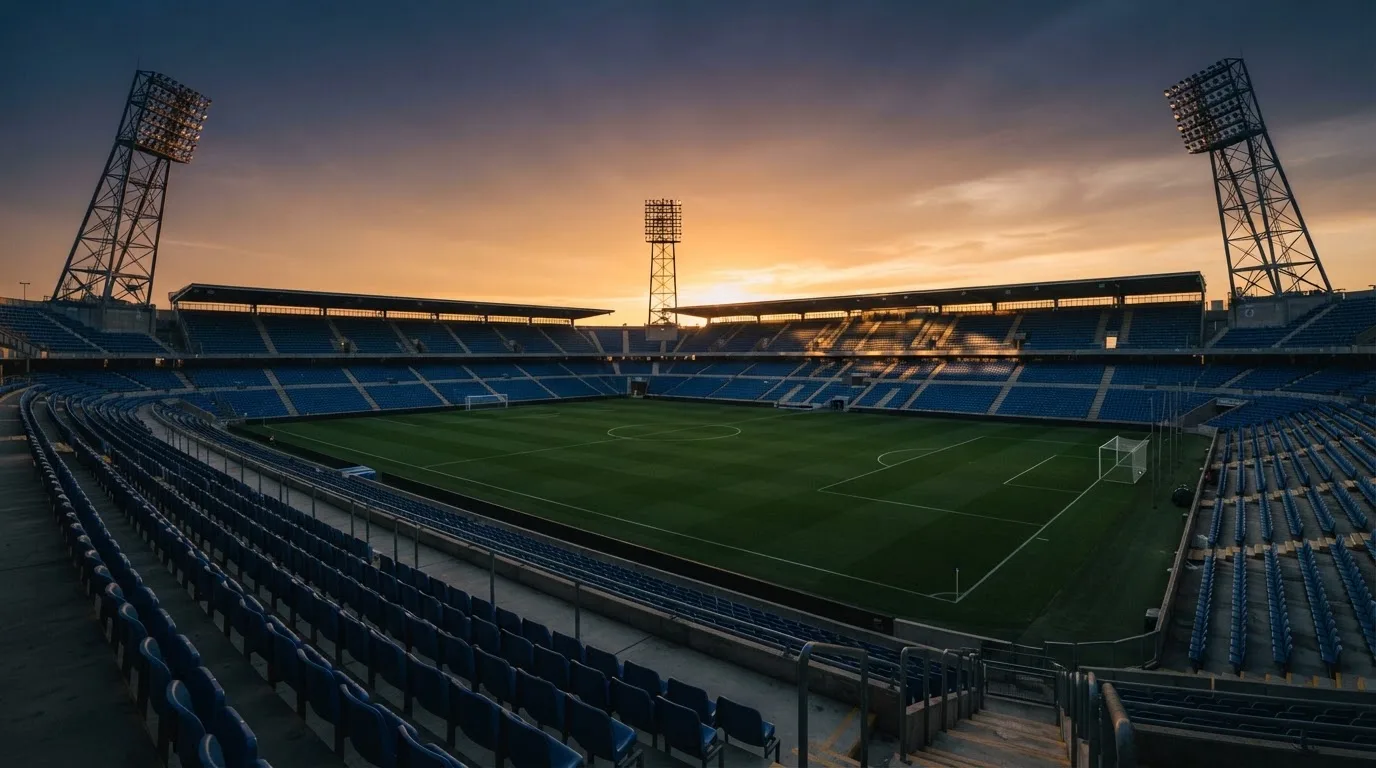 Un estadio de fútbol vacío con torres de iluminación al atardecer