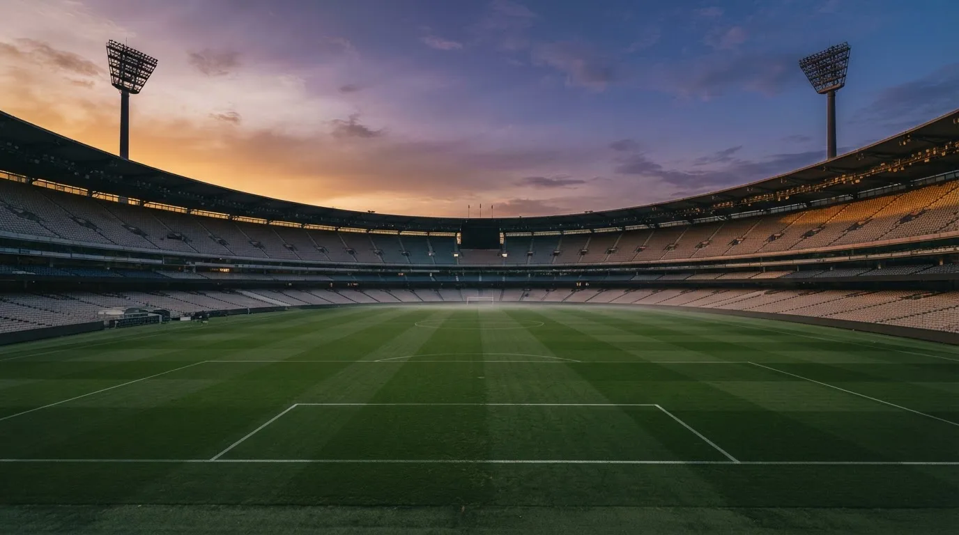 Un estadio de fútbol vacío con torres de iluminación al atardecer