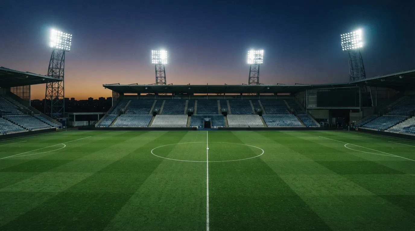 Un estadio de fútbol vacío con torres de iluminación al atardecer