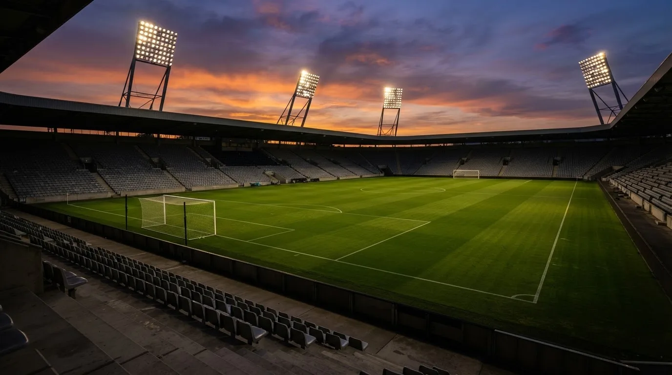 Un estadio de fútbol vacío con torres de iluminación al atardecer