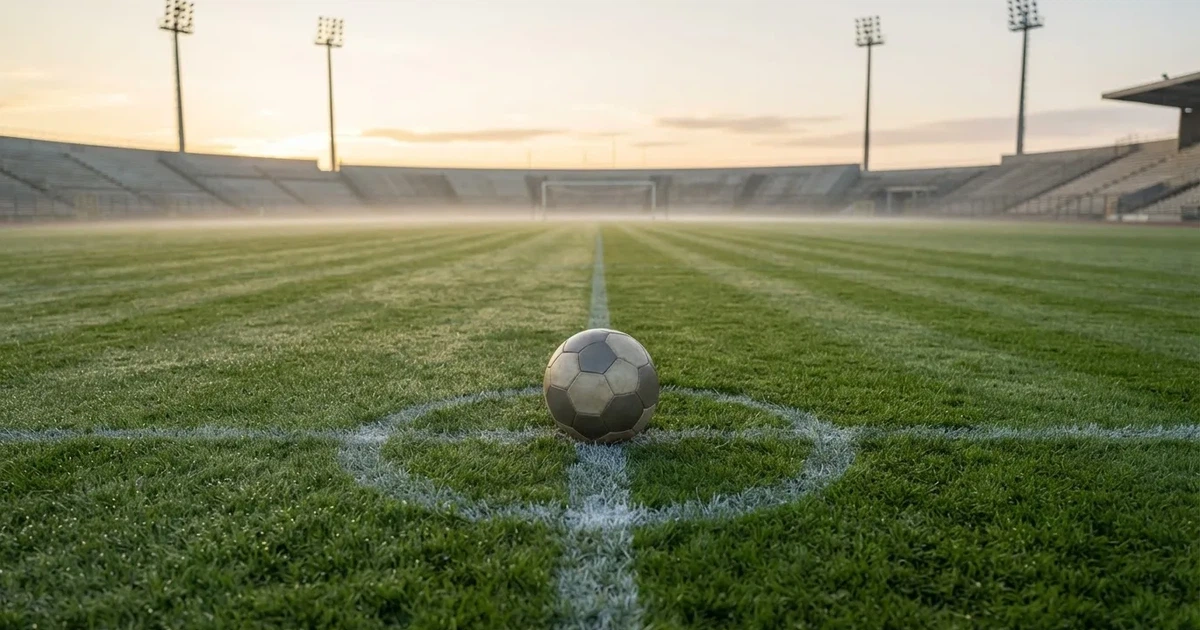 Un balón en el punto central de un campo de césped a la luz de la mañana