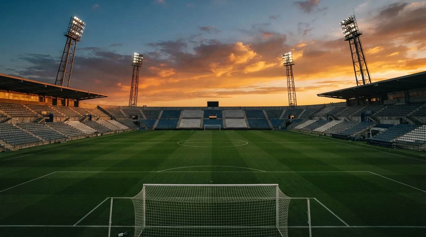 Un estadio de fútbol vacío con torres de iluminación al atardecer