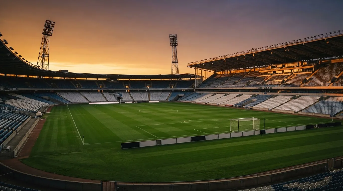 Un estadio de fútbol vacío con torres de iluminación al atardecer