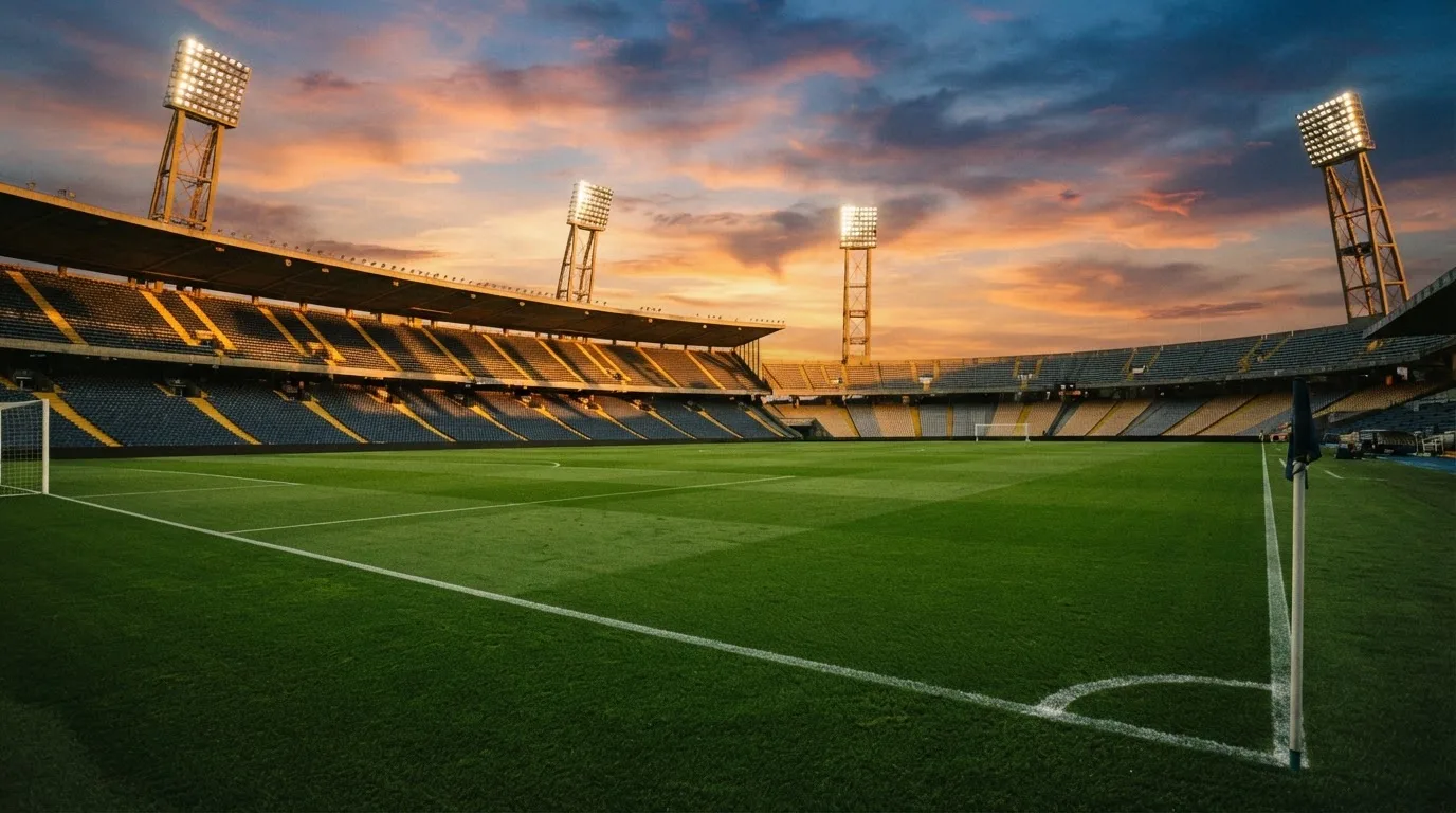 Un estadio de fútbol vacío con torres de iluminación al atardecer