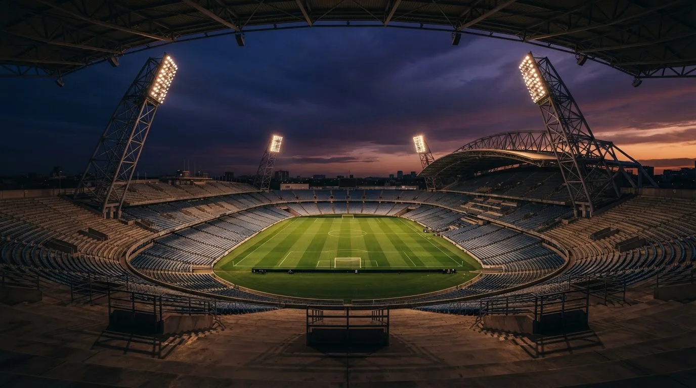 Un estadio de fútbol vacío con torres de iluminación al atardecer